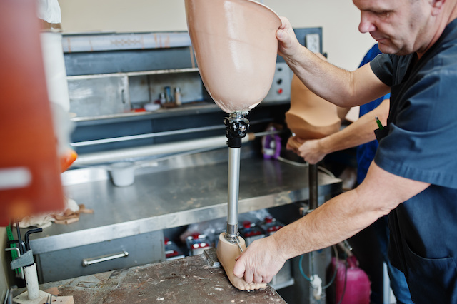Two prosthetist man workers making prosthetic leg while working in laboratory.
